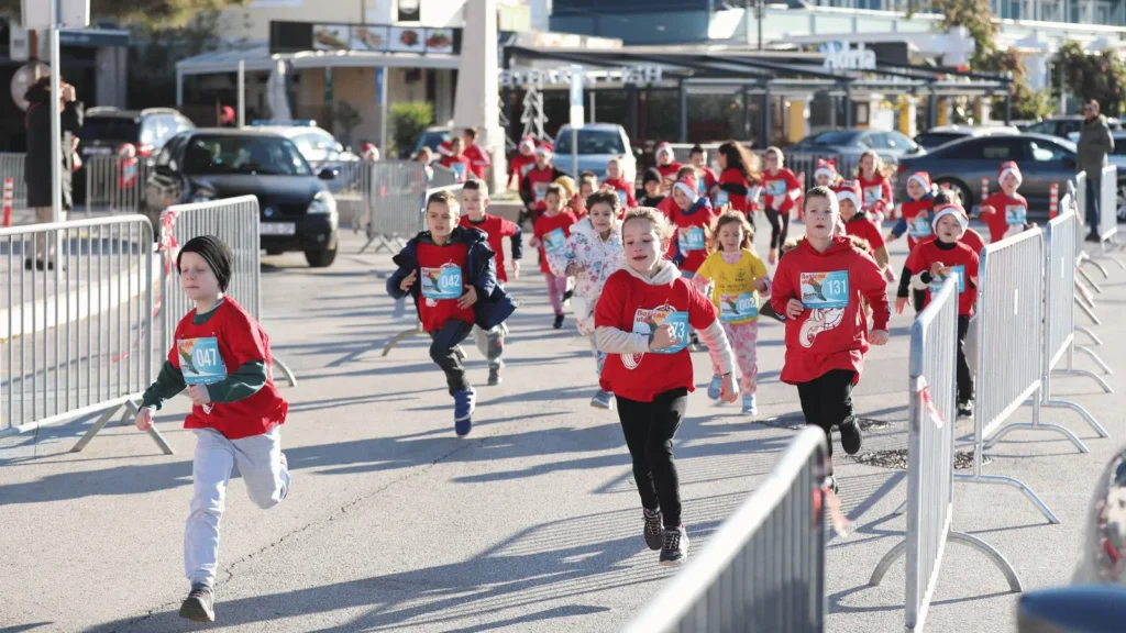 Trkači na Božićnoj utrci u Biogradu na Moru 2025. s božićnim kapama i startnim brojevima
