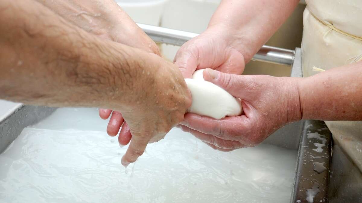 Ruke osobe koja nanosi novi sloj silikonskog brtvila oko ruba kade, izbliza.