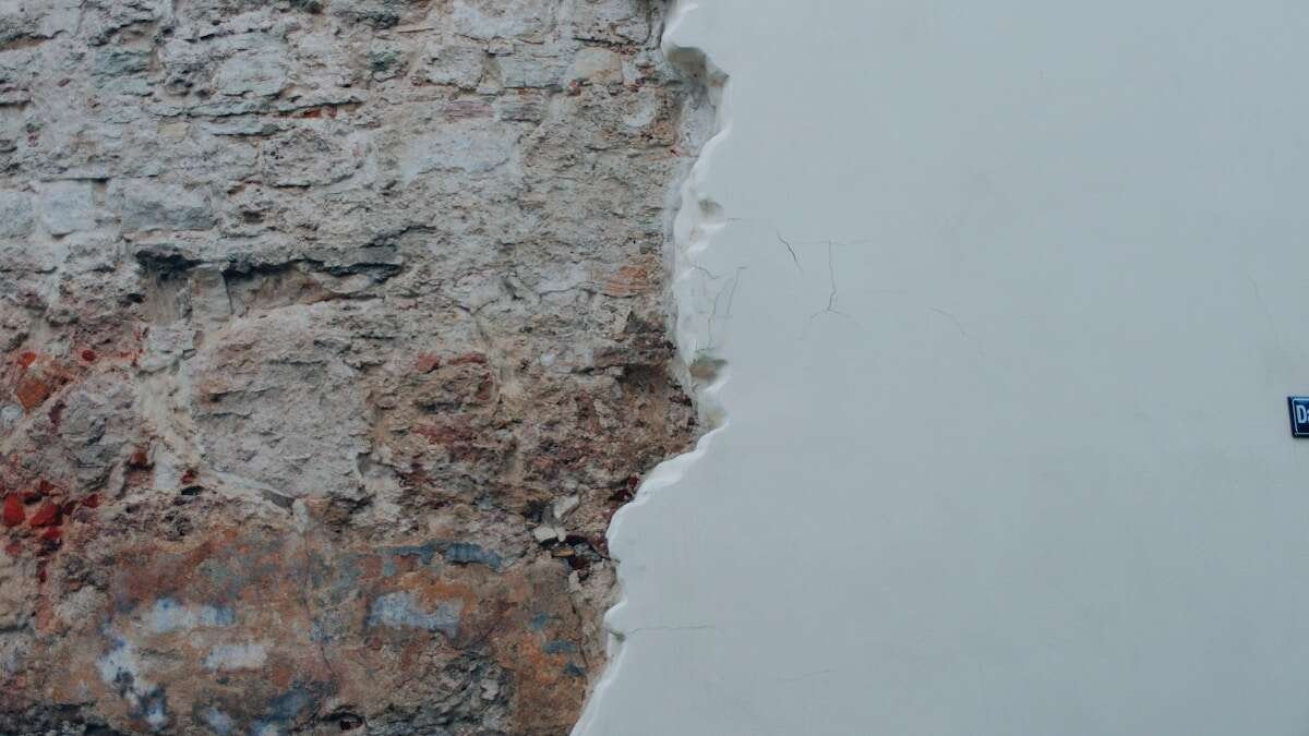 Detaljan pogled na osobu koja nanosi glet masu na rupu u zidu koristeći gletericu.