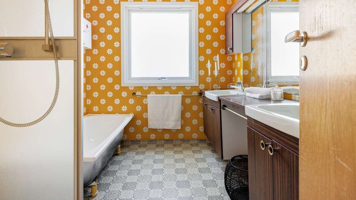 Osoba čisti pločice u kupaonici spužvom i sredstvom za čišćenje, pripremajući površinu za silikonsko brtvilo.