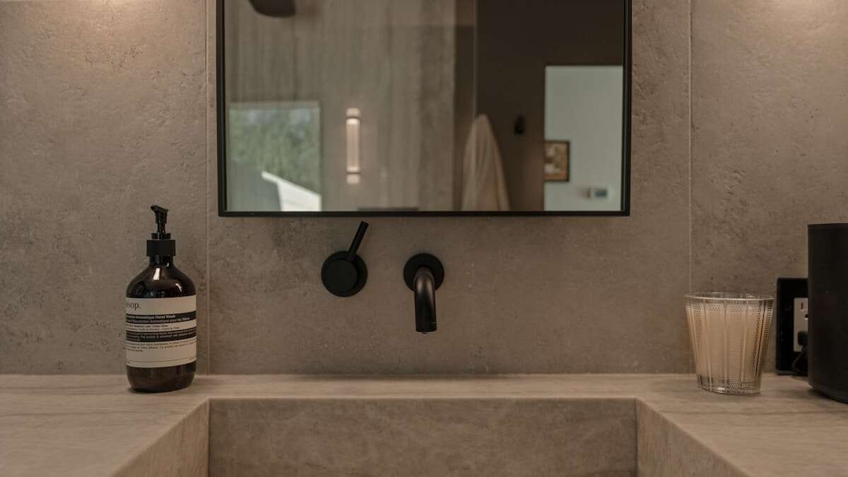 Osoba čisti plijesan u kupaonici spužvom, prikazano je uklanjanje plijesni s pločica.