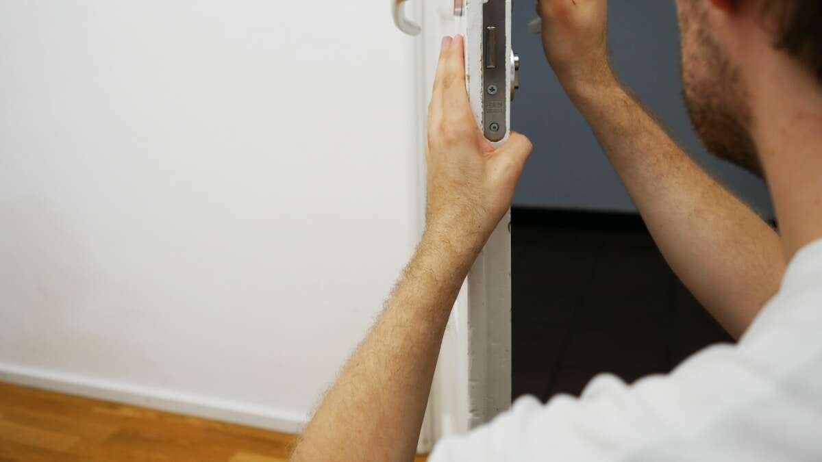 Osoba nanosi ulje na šarke vrata kako bi ih utišala, praktičan korak u održavanju vrata.