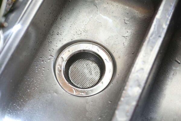 Bliski prikaz začepljenog kuhinjskog sudopera s vodom koja se ne odvodi, prikazuje uobičajeni problem u domaćinstvu.