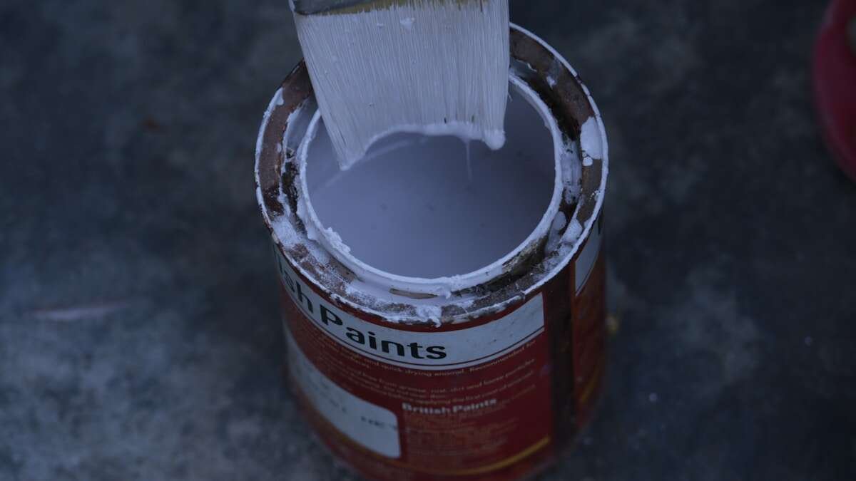 Konceptualna fotografija limenki boje s kapljicama boje na neutralnoj podlozi, simbolizirajući zbrinjavanje otpada.