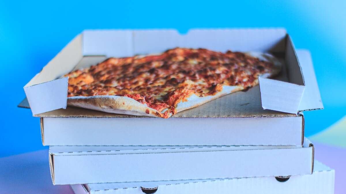 Konceptualna slika masne kutije za pizzu s prekriženim simbolom recikliranja, ilustrirajući neprikladnost takve ambalaže za recikliranje.