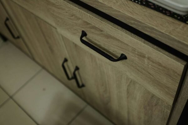 Povećan prikaz šarki na kuhinjskom ormariću, detalji vijaka i mehanizma za podešavanje.