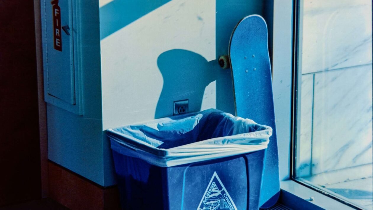 Bliski prikaz plave reciklažne kante za papir u uredu, s jasnom oznakom za papirni otpad.