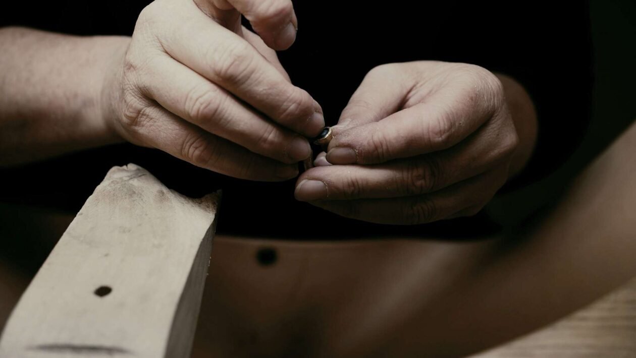 Ruke nanose vosak na izgrebanu površinu drvenog namještaja, detaljan prikaz procesa popravka.