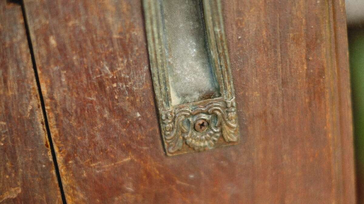 Ruka nanosi ulje na šarke vrata kako bi spriječila škripanje, detaljan pogled na popravak.