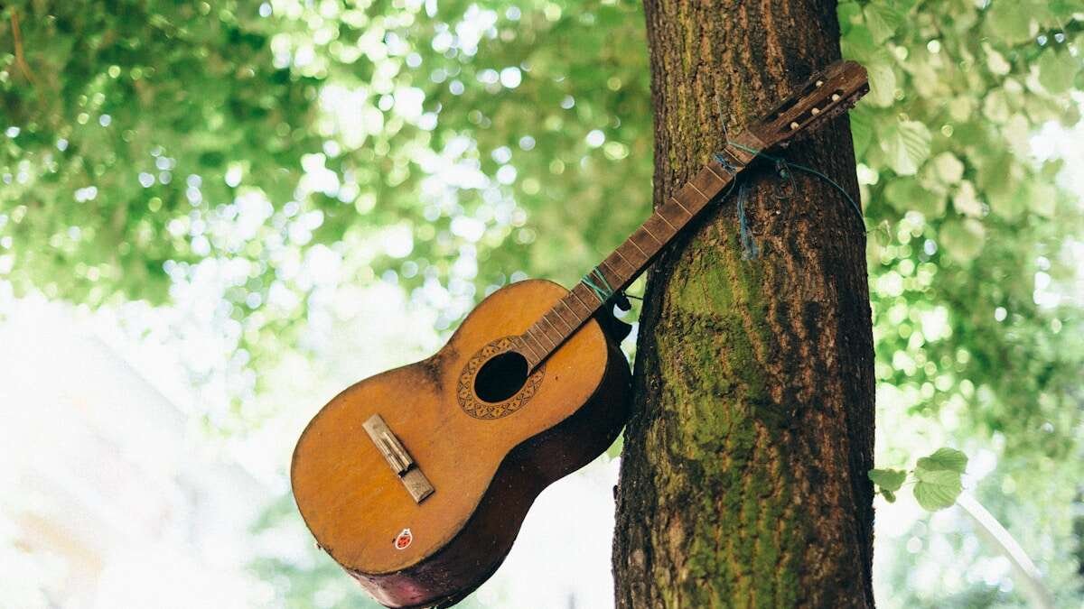 Vintage akustična gitara s prirodnom patinom i detaljima, evocira povijest i dugovječnost ovog instrumenta.
