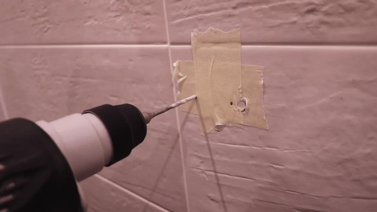 Uvod Bušenje rupa u pločicama i žbuci može biti pravi izazov, čak i za iskusne majstore. Pločice su krhke i sklone pucanju, a nepravilno bušenje može dovesti do ozbiljnih oštećenja koja zahtijevaju skup popravak. Isto tako, nepravilno bušenje može uzrokovati da rupa ne bude ravna, što može utjecati na estetiku i funkcionalnost prostora. Kako biste izbjegli ove probleme, važno je poznavati pravilne tehnike i koristiti odgovarajuće alate. U ovom članku istražit ćemo korake i trikove koji će vam pomoći da izbušite rupu upravo onako kako želite – ravno i bez oštećenja. Naučit ćete kako pravilno pripremiti površinu, odabrati pravi alat i primijeniti tehniku koja osigurava uspjeh. Bez obzira jeste li početnik ili imate iskustva, ove praktične savjete možete lako primijeniti u praksi. Uz detektore, specijalne bušilice i jednostavne zaštitne trikove, možete izbušiti rupu bez straha od pucanja pločica ili oštećenja žbuke. Krenimo s osnovama kako biste bili sigurni u svaki svoj korak. Što to znači Bušenje ravne i čiste rupe bez oštećenja znači da ste uspjeli probiti pločicu, zid ili žbuku bez stvaranja pukotina, neravnina ili mrlja. To je posebno važno u prostorijama poput kupaonica i kuhinja, gdje su pločice često dekorativni, ali i funkcionalni elementi. Oštećenje pločica ne samo da narušava estetiku prostora već može izazvati i probleme poput prodiranja vlage. Kada govorimo o “ravnoj rupi”, mislimo na rupu koja je izbušena okomito ili pod točno željenim kutom, bez odstupanja. Ovo je ključno za pravilno postavljanje vijaka, tipli ili nosača. Na primjer, ako postavljate nosač za ručnik u kupaonici, a rupa nije ravna, nosač može stajati ukoso, što nije samo neestetski već i nepraktično. Razumijevanje materijala s kojim radite također je ključ uspjeha. Pločice su često izrađene od keramike, porculana ili stakla, a svaki od ovih materijala ima svoje posebnosti. Keramika je mekša i lakša za bušenje, dok je porculan tvrđi i zahtijeva više pažnje. Žbuka, s druge strane, može biti mekana ili tvrda ovisno o vrsti i starosti zida. Kako funkcionira Priprema površine Priprema je ključna. Prvo, očistite površinu pločice ili zida kako biste uklonili prašinu i masnoće. Ovaj korak osigurava dobru vidljivost i sprječava klizanje bušilice. Ako bušite pločice, označite točno mjesto gdje želite napraviti rupu koristeći marker ili komad ljepljive trake. Ljepljiva traka također može pomoći u sprječavanju pucanja jer smanjuje vibracije. Odabir alata Pravi alati čine razliku. Za bušenje pločica preporučuje se uporaba bušilice s podesivom brzinom i svrdla za keramiku ili staklo. Ova svrdla obično imaju vrh obložen dijamantima ili volfram-karbidom, što ih čini dovoljno oštrim i izdržljivim. Ako bušite žbuku ili zid, koristite svrdla za beton i razmislite o korištenju udarne bušilice. Osoba priprema zid za bušenje pomoću zaštitne trake i ravnala, osiguravajući preciznost i zaštitu od oštećenja. Photo by Ömer Haktan Bulut on Unsplash Tijekom bušenja Prilikom bušenja, ključ je strpljenje. Započnite s niskom brzinom kako biste izbjegli pregrijavanje svrdla i oštećenje pločice. Kada probijete glazuru pločice, možete povećati brzinu, no uvijek pazite da ne forsirate bušilicu. Ako osjetite otpor, stanite i provjerite stanje svrdla i površine. Za dodatnu preciznost, koristite vodilicu za bušenje koja drži bušilicu stabilnom. Ovo je posebno korisno za početnike ili kod bušenja na klizavim površinama. Praktični primjeri Primjer 1: Postavljanje ogledala u kupaonici. Ako trebate izbušiti rupe za nosače ogledala, prvo označite točke na pločicama. Zalijepite komad trake preko oznake kako biste spriječili klizanje svrdla. Koristite svrdlo za keramiku i počnite bušiti na niskoj brzini. Nakon što probijete pločicu, zamijenite svrdlo onim za beton kako biste nastavili bušenje u zidu. Primjer 2: Montaža kuhinjskih polica. Kod bušenja kroz keramičke pločice u kuhinji, postupak je sličan – koristite marker za precizno označavanje, ljepljivu traku za zaštitu i svrdla za keramiku i beton. Također, uvijek provjerite ima li ispod pločice električnih instalacija pomoću detektora. Primjer 3: Bušenje rupa na vanjskim zidovima. Ako bušite kroz žbuku ili opeku, koristite udarnu bušilicu i svrdla za beton. Pripremite područje oko mjesta bušenja kako biste uhvatili prašinu, primjerice pomoću ljepljive trake postavljene ispod rupe. Benefiti i primjena Pravilno bušenje ne samo da osigurava estetski rezultat već i produljuje vijek trajanja pločica i zida. Osim toga, pravilno izbušene rupe omogućuju sigurno postavljanje nosača, polica, ogledala i drugih elemenata. Ovo je posebno važno u prostorima koji su izloženi vlazi ili čestim promjenama temperature, poput kupaonica i vanjskih zidova. Primjena ovih tehnika nije ograničena samo na kućanstva. Mnoge industrije, uključujući građevinu i dizajn interijera, oslanjaju se na precizno bušenje kako bi osigurale kvalitetu i sigurnost svojih projekata. Na primjer, postavljanje staklenih pregrada u uredima zahtijeva precizno bušenje rupa kroz staklo i pločice. Osim toga, pravilno bušenje smanjuje rizik od skupih popravaka. Puknuta pločica često zahtijeva zamjenu cijele plohe, što može biti skupo i dugotrajno. Primjenom pravilnih tehnika izbjegavate te probleme. Blizak prikaz svrdla za bušenje porculanskih pločica, ilustrirajući specijalizirani alat za izbjegavanje pucanja pločica. Photo by Declan Sun on Unsplash Najčešća pitanja Kako spriječiti klizanje bušilice na pločici? Zalijepite komad ljepljive trake preko mjesta gdje želite bušiti. Traka stvara trenje i sprječava klizanje svrdla. Također, koristite bušilicu s niskom brzinom na početku. Koje svrdlo koristiti za pločice? Koristite svrdla s vrhom od volfram-karbida ili dijamanta. Ova svrdla su posebno dizajnirana za rad s tvrdim i krhkim materijalima poput pločica. Što učiniti ako pločica pukne? Ako pločica pukne, odmah prekinite bušenje. Uklonite oštećenu pločicu i zamijenite je novom. Prije ponovnog bušenja, provjerite je li svrdlo ispravno i koristite zaštitne mjere poput ljepljive trake. Zaključak Bušenje rupa u pločicama i žbuci može zvučati zastrašujuće, ali uz pravu tehniku, alate i pripremu, možete izbjeći pucanje i oštećenja. Ključ uspjeha je u strpljenju, preciznosti i korištenju odgovarajuće opreme. Bez obzira radite li na renovaciji kupaonice, postavljanju kuhinjskih polica ili instaliranju dekoracija, ovim savjetima osigurat ćete profesionalne rezultate. Sljedeći put kada se suočite s izazovom bušenja, prisjetite se ovog vodiča i budite sigurni da ćete posao obaviti bez stresa i neugodnih iznenađenja. Više ovakvih tema pročitajte u kategoriji: DIY i uređenje doma