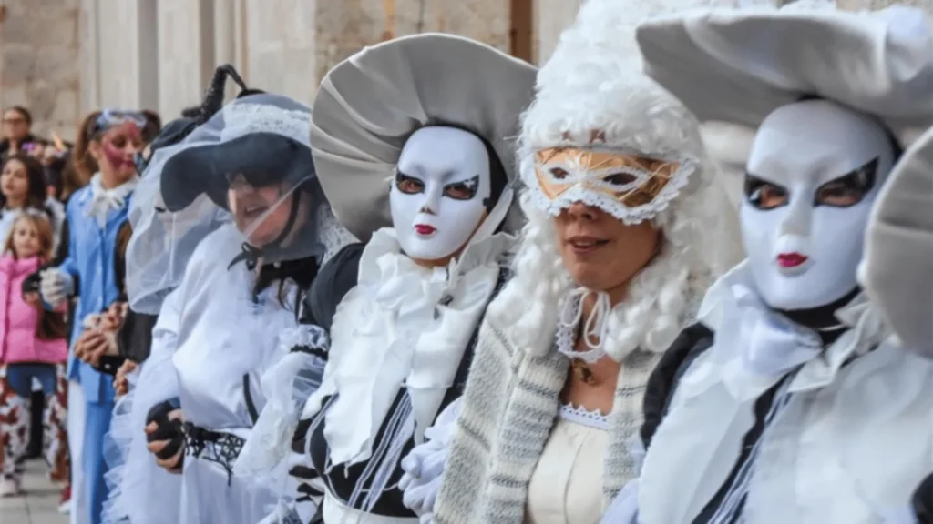 Sudionici Paškog zimskog karnevala u tradicionalnim maskama na gradskom trgu u Pagu