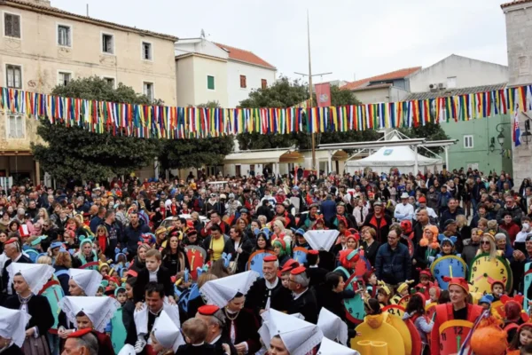 Sudionici Paškog zimskog karnevala u tradicionalnim maskama na gradskom trgu u Pagu