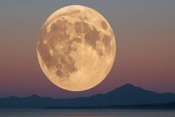 Veliki Mjesec nisko nad horizontom koji izgleda neobično ogroman