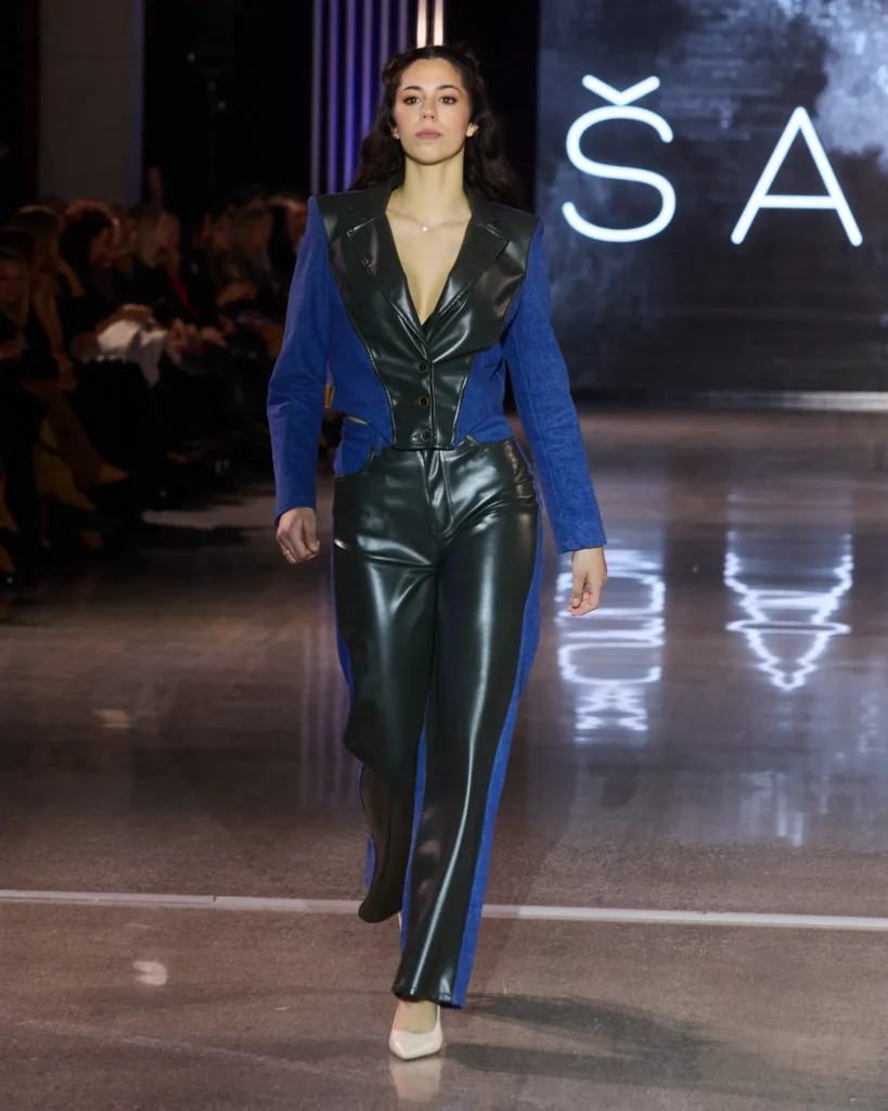 ŠARGI Denim plavi kombinezon s kontrastnim kožnim panelima i dubokim V izrezom.