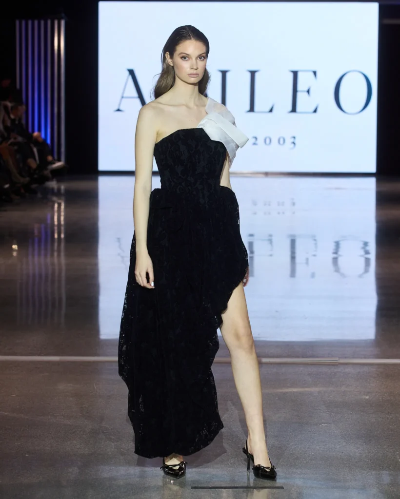 Crna večernja haljina s bijelim voluminoznim detaljem preko ramena predstavljena na Arileo pisti.