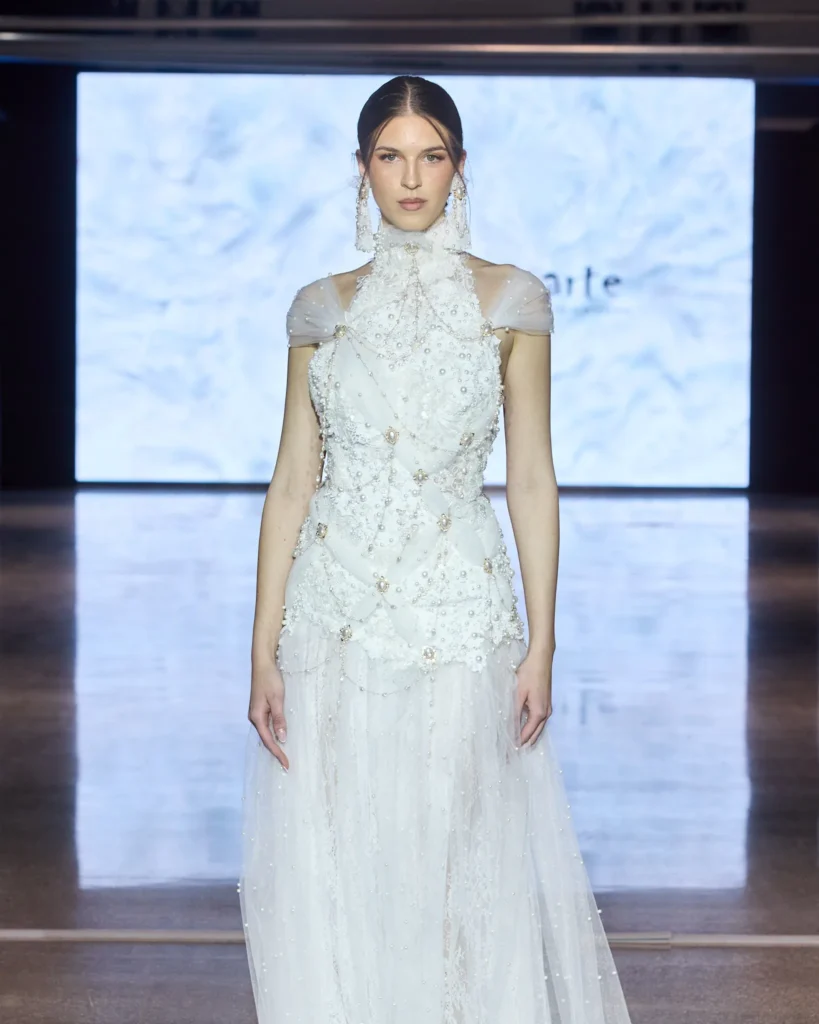 Bijela večernja haljina s bisernim vezom i prozračnim slojevima predstavljena u ARTE kolekciji.