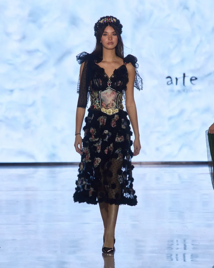 Crna čipkasta haljina s floralnim motivima i ukrasnim korzetnim detaljem na modnoj pisti ARTE kolekcije.