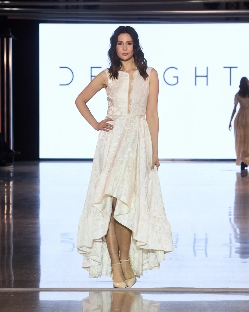 Asimetrična bijela haljina s teksturiranim materijalom i visokim prednjim rezom.