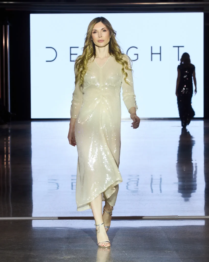 Bijela midi haljina sa sjajnim površinskim efektom i prozirnim slojevima u pokretu.