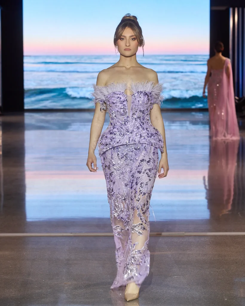 Lila haljina spuštenih ramena ukrašena perjem i čipkom.