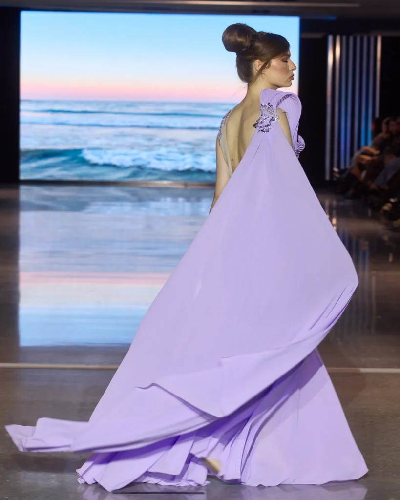 Lila haljina s bogatim pokretnim tilom prikazana u kretanju na pisti.