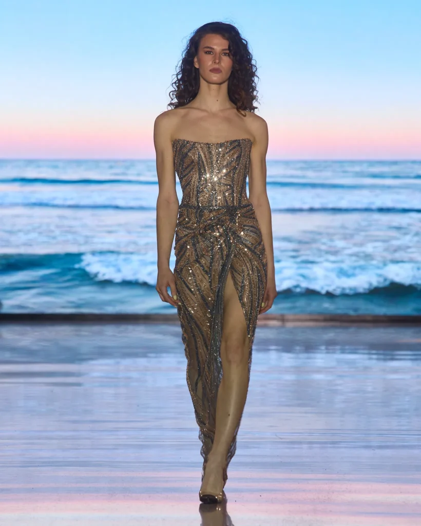 Zlatna večernja haljina prekrivena šljokicama s korzetnim krojem i prednjim prorezom.