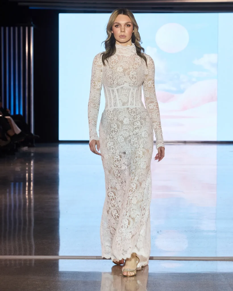 Bijela maksi haljina od čipke s dugim rukavima i strukturiranim korsetnim strukom.