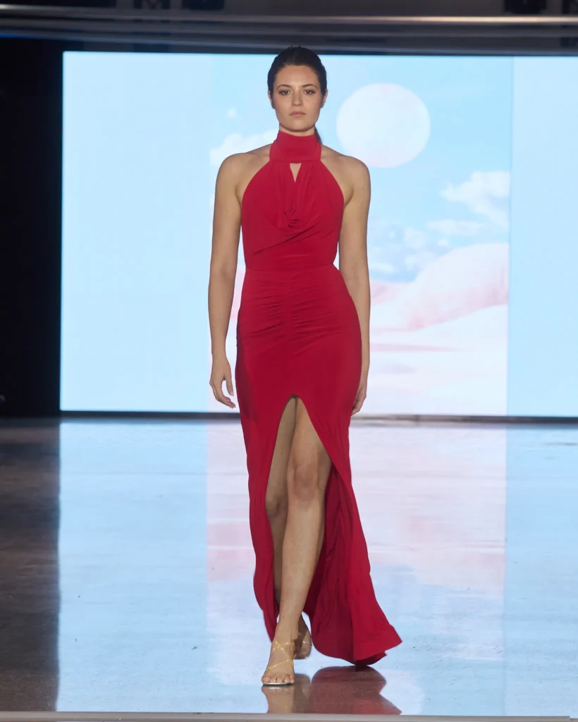 Crvena haljina s halter izrezom, drapiranim linijama i visokim prednjim prorezom.