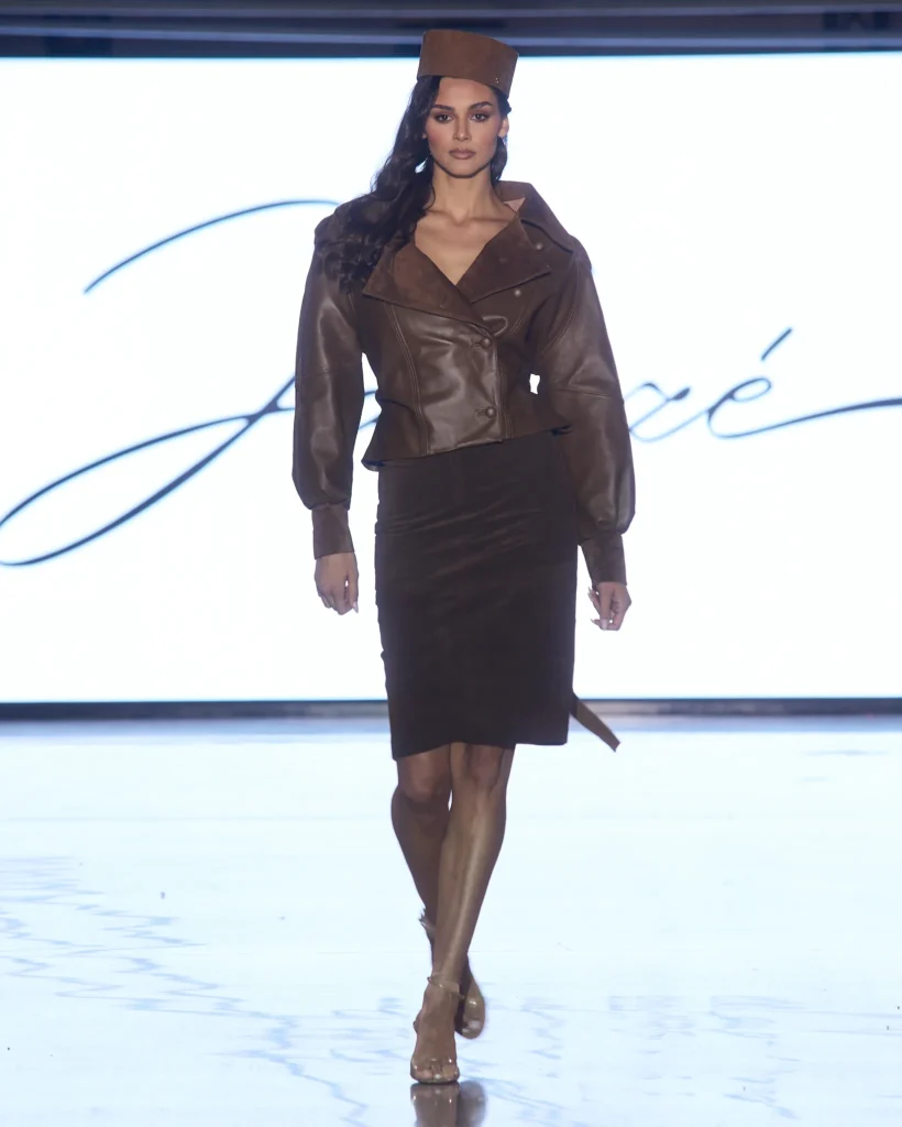 Smeđi kožni set s midi suknjom i strukturiranom jaknom, upotpunjen modnom kapom.