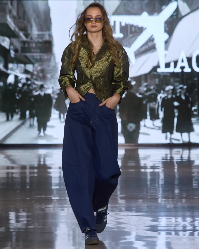 Maslinasti metalik sako u kombinaciji s plavim širokim hlačama i sunčanim naočalama.