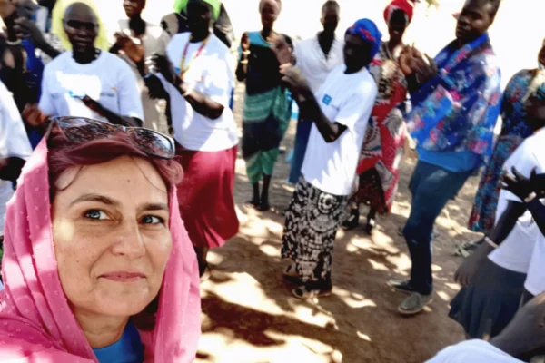 Žena s ružičastom maramom snima selfie s grupom ljudi koji plješću u pozadini