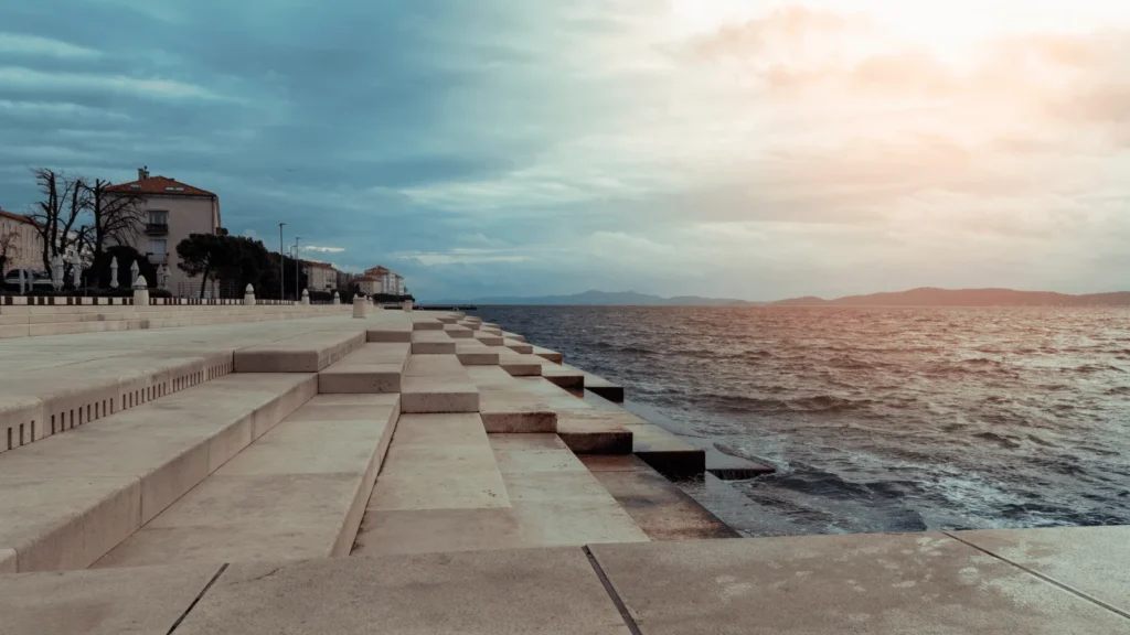 People gathered at the Sea Organ Zadar sunset, watching the sun dip into the Adriatic while waves create soft sounds.