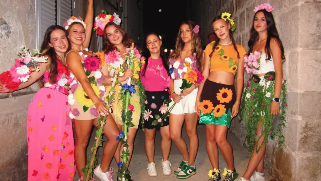 Sedam djevojaka odjevenih u haljine ukrašene cvijećem i lišćem, poziraju za fotografiju