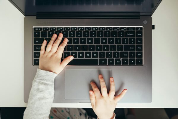 Ruka djeteta na tipkovnici prijenosnog računala dok je online