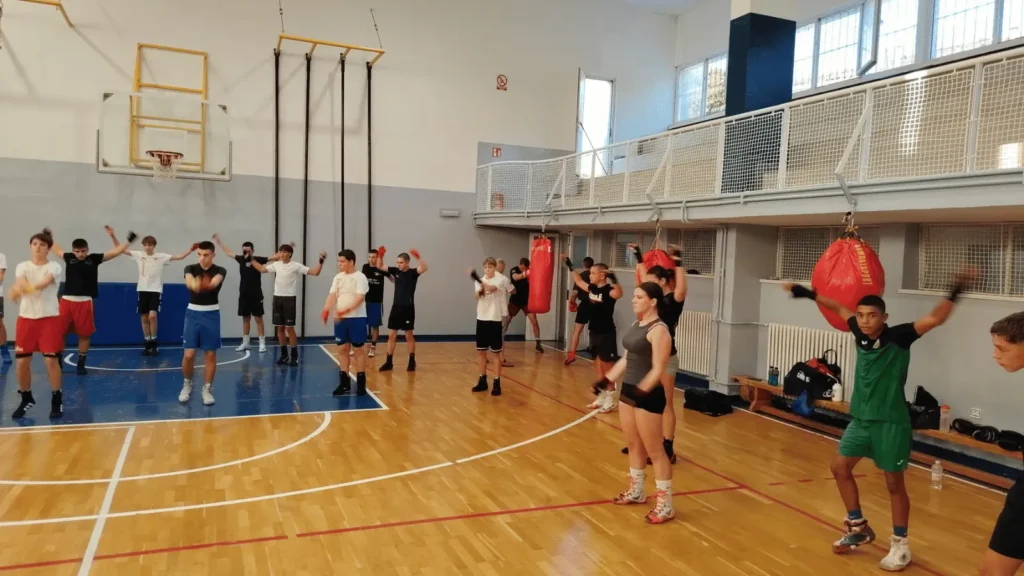 Grupa mladih ljudi vježba u dvorani s boksačkim vrećama u pozadini