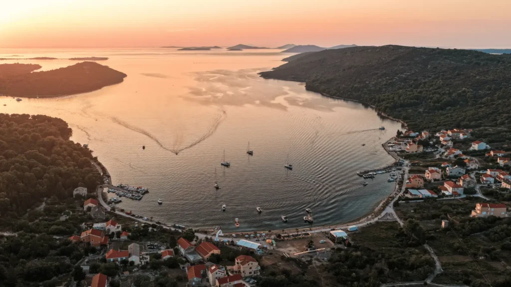Zračni pogled na zaljev s brodovima i selom na obali pri zalasku sunca