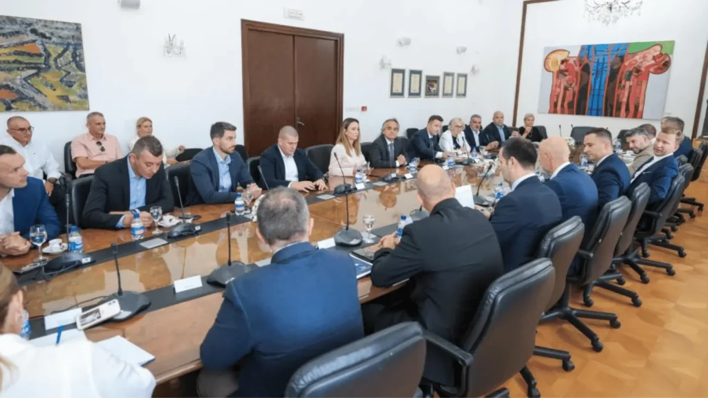 Skupina ljudi sjedi za dugim stolom na sastanku
