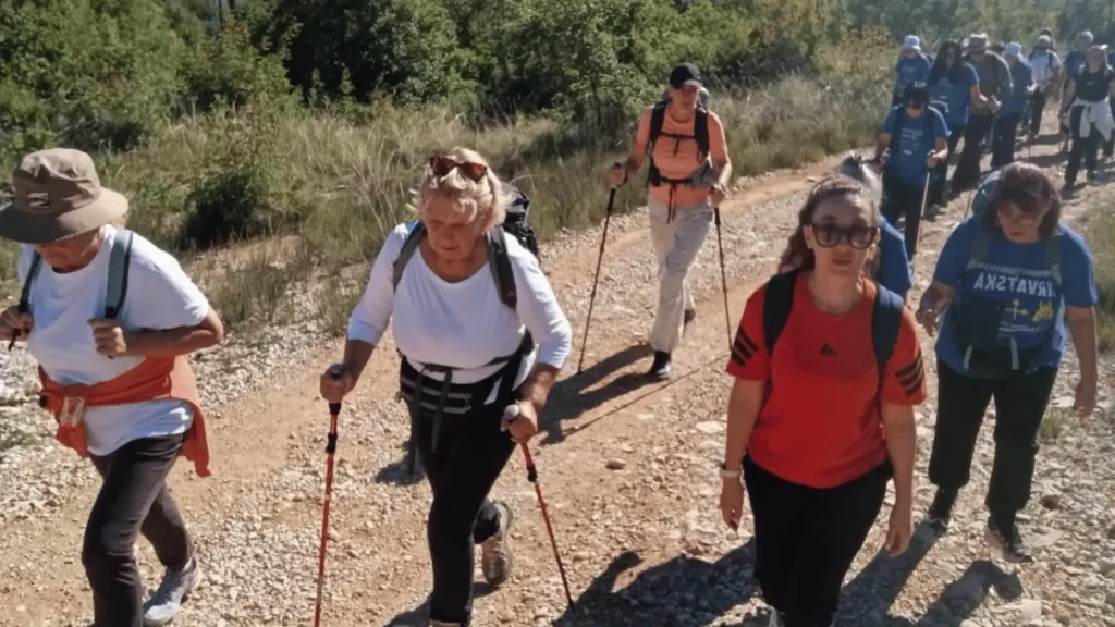 Grupa ljudi planinari po zemljanom putu u brdovitom području