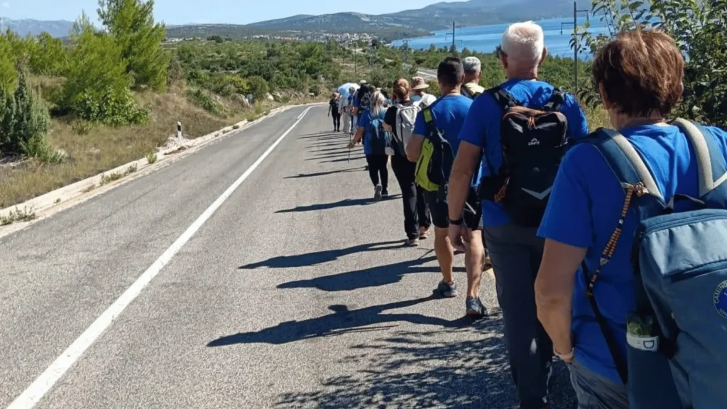 Grupa planinara hoda niz cestu uz obalu mora