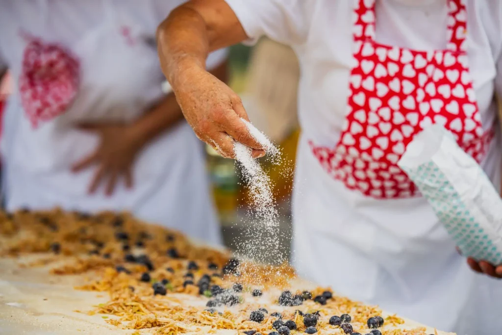 Žena posipa šećerom smjesu za desert s borovnicama