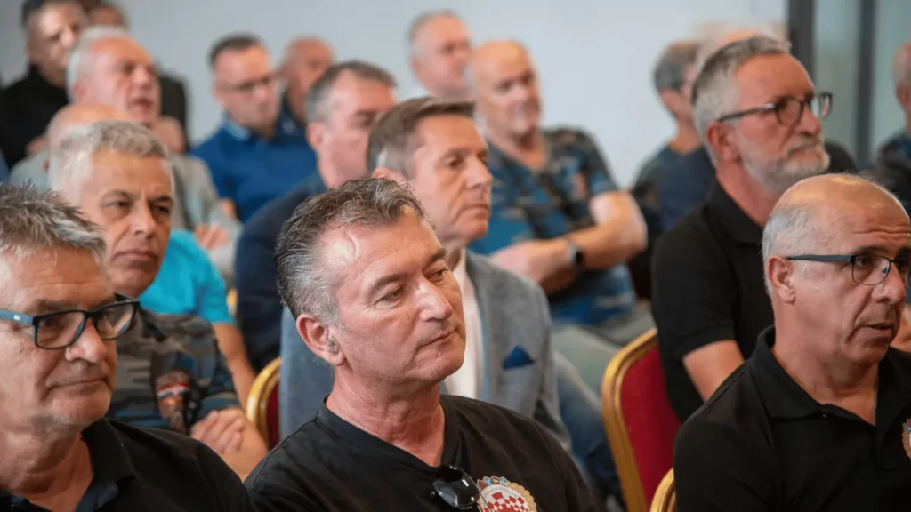 Grupa muškaraca sluša na sastanku