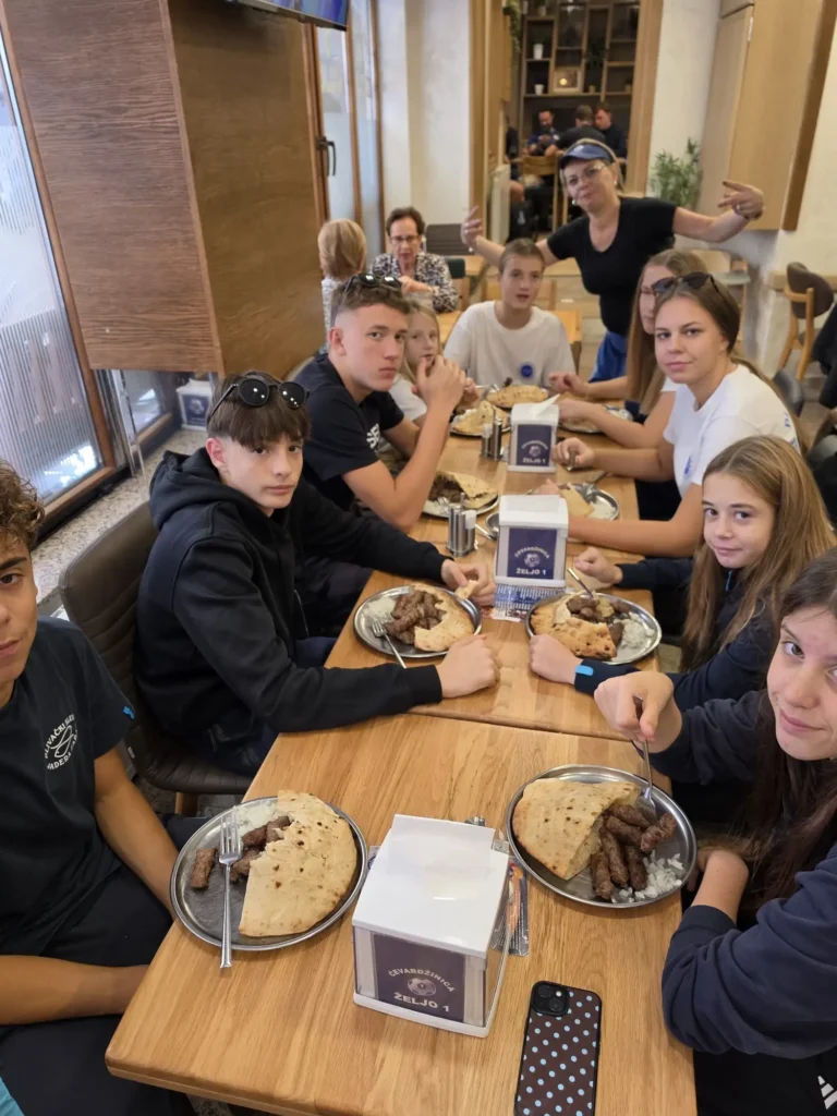 Grupa mladih ljudi jede ćevape u restoranu