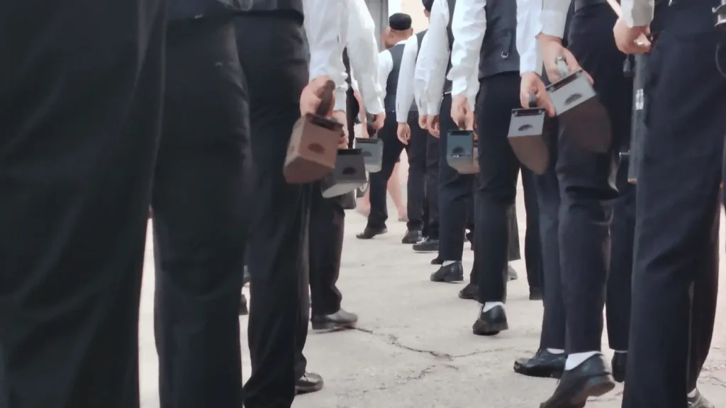 Ljudi u crnim hlačama i bijelim košuljama drže male kutije