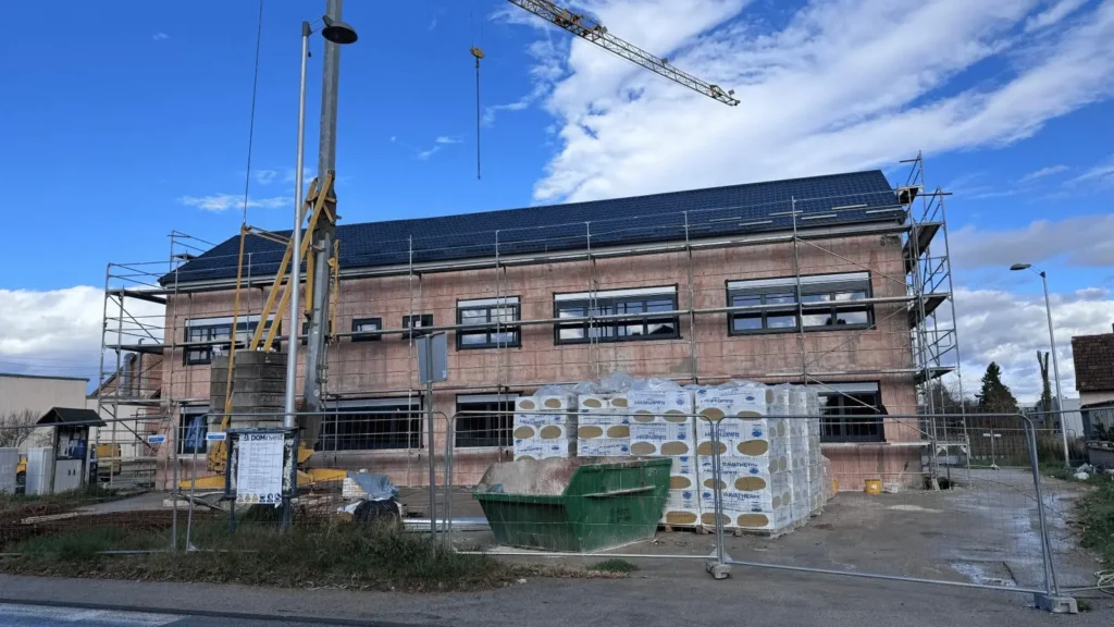 Građevina u fazi gradnje, s dizalicom u pozadini i građevinskim materijalom poredana na gradilištu
