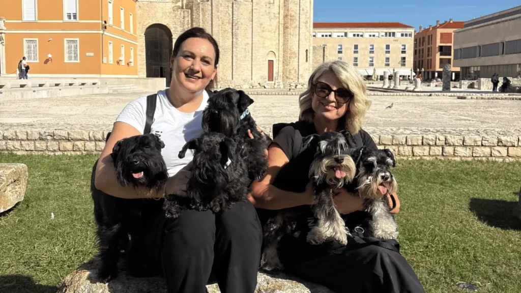 Dvije žene sjede vani s po dva patuljasta šnaucera u krilu